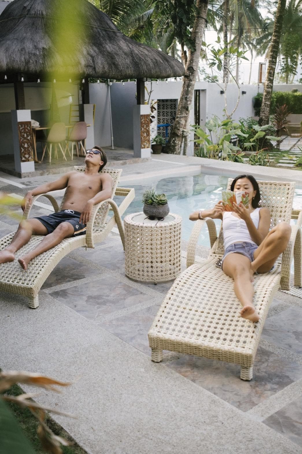 Two guests relaxing on loungers by a resort pool